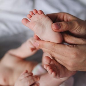 A close-up of a parent's hands gently massaging a baby's feet, showcasing tenderness and care.