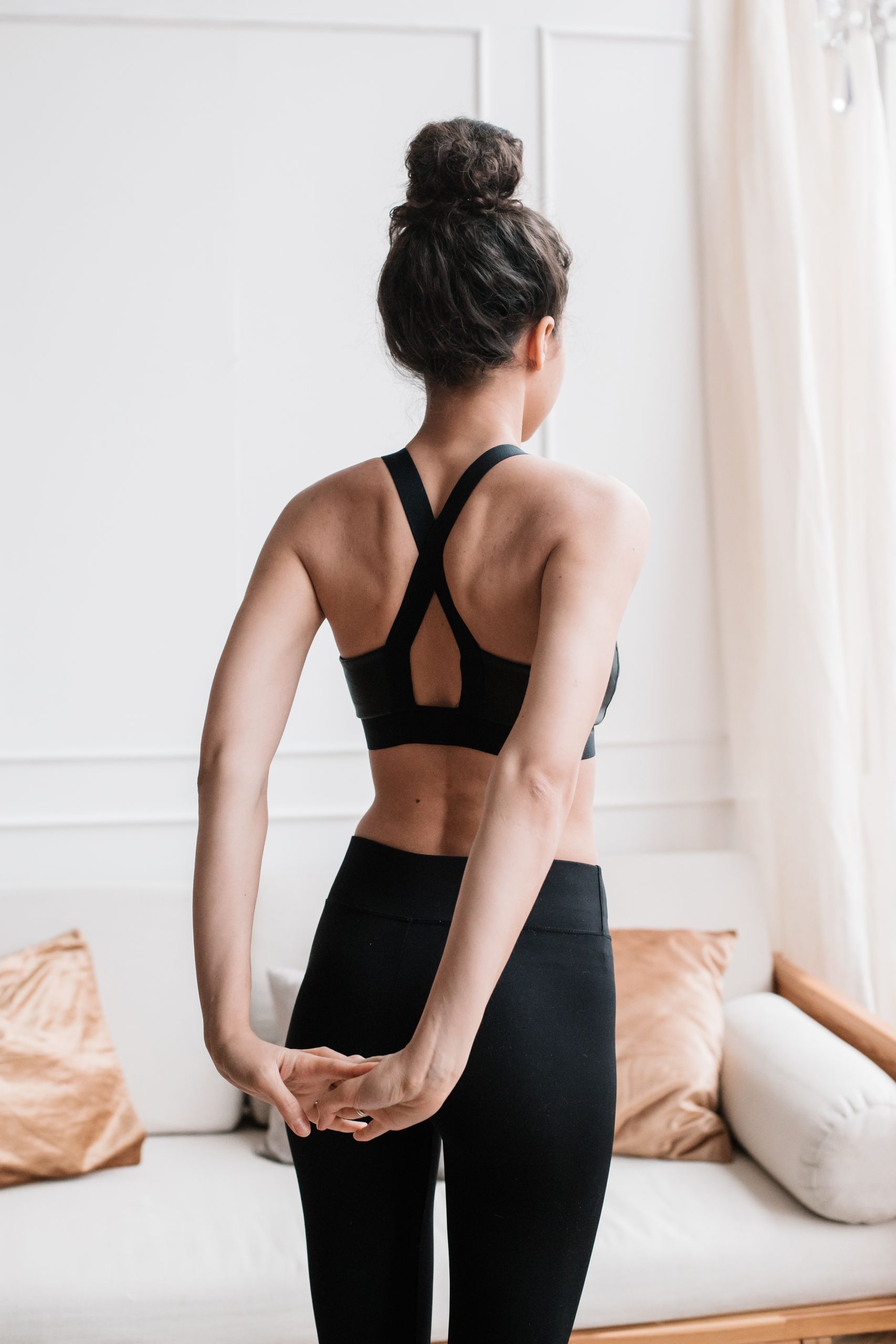 Woman performing a yoga stretch at home, promoting a healthy and relaxed lifestyle.